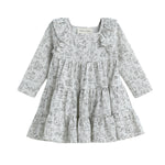 The Mabel + Honey Doggie Doodles Dress Long Sleeve Print Tiered Dress features a light gray fabric adorned with a charming black outline dog print. Designed with playful ruffles on the shoulders and a tiered skirt, this girls’ fall dress is perfect for little animal lovers.