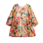The Mabel and Honey Watercolor Whimsey Long Sleeve Floral Tiered Ruffle Waist Dress is a loose-fit children’s dress adorned with a vibrant watercolor floral pattern in shades of pink, yellow, orange, and green. It features gathered side pockets and a charming tiered skirt for added style.