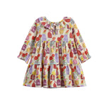 The Petal Pots Long Sleeve Print Ruffle Collar Tiered Dress by Mabel and Honey features a soft cream stretch knit fabric, a relaxed fit, and playful tiered layers. Adorned with a vibrant pattern of cupcakes, candies, bows, and touches of floral print in red, purple, and yellow, this toddler dress is finished with long sleeves and a charming ruffled collar. Displayed on a white background.