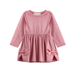 The Bowtiful Blush Dress Long Sleeve Solid A Line Bow Detail Dress by Mabel + Honey is a girls’ dress in blush pink, made of soft ribbed velour with long sleeves. It features a gathered waist and two large bows near the hem of the skirt, adding a charming touch, and is shown beautifully against a white background.