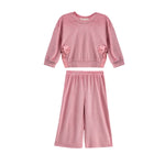 The Bowtiful Blush Long Sleeve Solid Bow Tie Side Slit Top and Pant Set by Mabel and Honey is a kids’ blush two-piece outfit featuring a pink ribbed knit top with long sleeves and delightful bow tie side slit details, paired with coordinating wide leg pants, displayed on a white background.