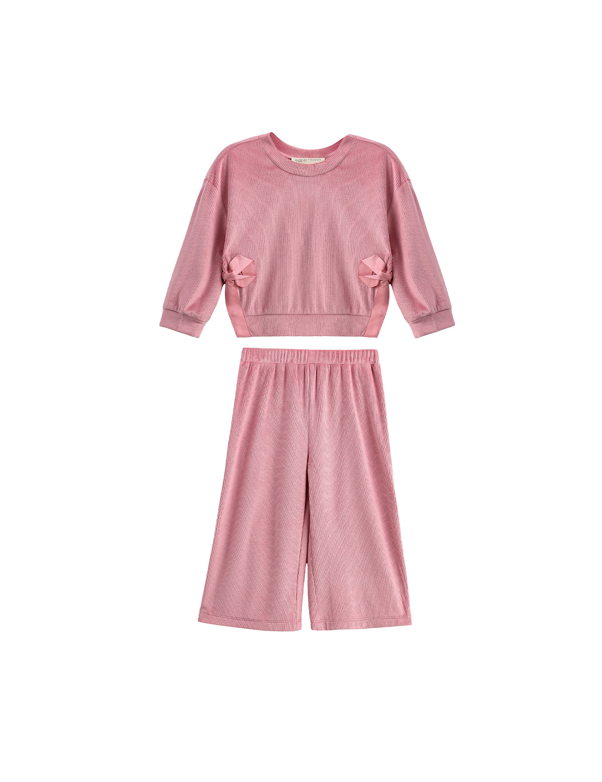 The Bowtiful Blush Long Sleeve Solid Bow Tie Side Slit Top and Pant Set by Mabel and Honey is a kids’ blush two-piece outfit featuring a pink ribbed knit top with long sleeves and delightful bow tie side slit details, paired with coordinating wide leg pants, displayed on a white background.