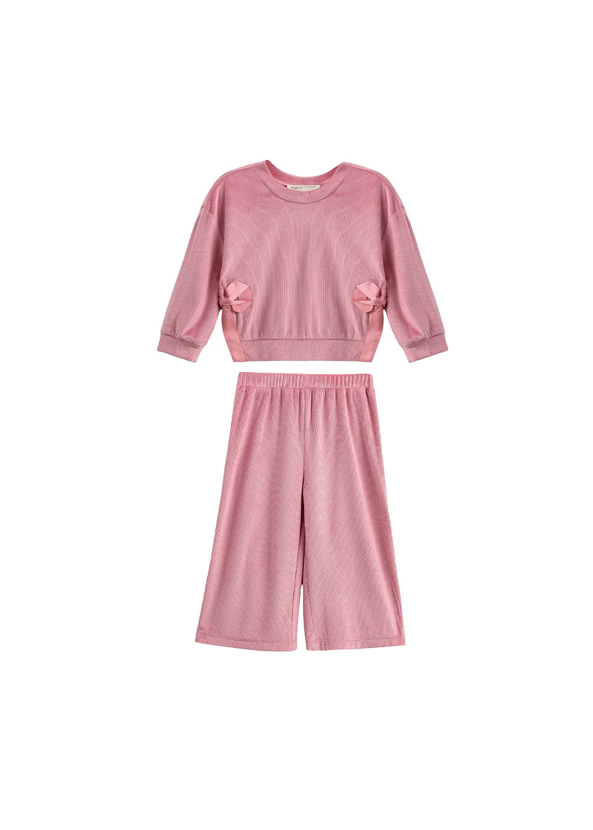 The Bowtiful Blush Long Sleeve Solid Bow Tie Side Slit Top and Pant Set by Mabel and Honey is a kids’ blush two-piece outfit featuring a pink ribbed knit top with long sleeves and delightful bow tie side slit details, paired with coordinating wide leg pants, displayed on a white background.