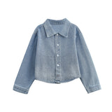 Mabel and Honey’s Long Sleeve Rhinestone Embellished Denim Cropped Jacket features a light blue wash, long sleeves, a pointed collar, front button closure, and rhinestone embellishments with a subtle faded pattern. The jacket offers a relaxed fit with plain cuffs.
