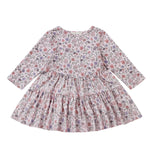 The Mabel and Honey Whimsical Wildflower Dress is a long-sleeve, knee-length A-line dress for children, showcasing a colorful wildflower print on a white background. It features a gathered waist, round neckline, and a charming ruffled tiered skirt.
