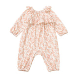 The Mabel and Honey Honey Petals Romper features long sleeves, a ruffled neckline, and a charming pink Honey Petals floral print on a white background. Crafted from soft stretch knit fabric, this straight leg romper is shown laid flat on a white surface.