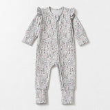 The Mabel + Honey Whimsical Wildflower Convertible Romper showcases long sleeves, straight legs, and charming ruffled shoulders, with a convenient zip-up front. Crafted from soft, stretchy knit fabric in a delicate pink and green ditsy floral print, this romper is displayed on a white background.