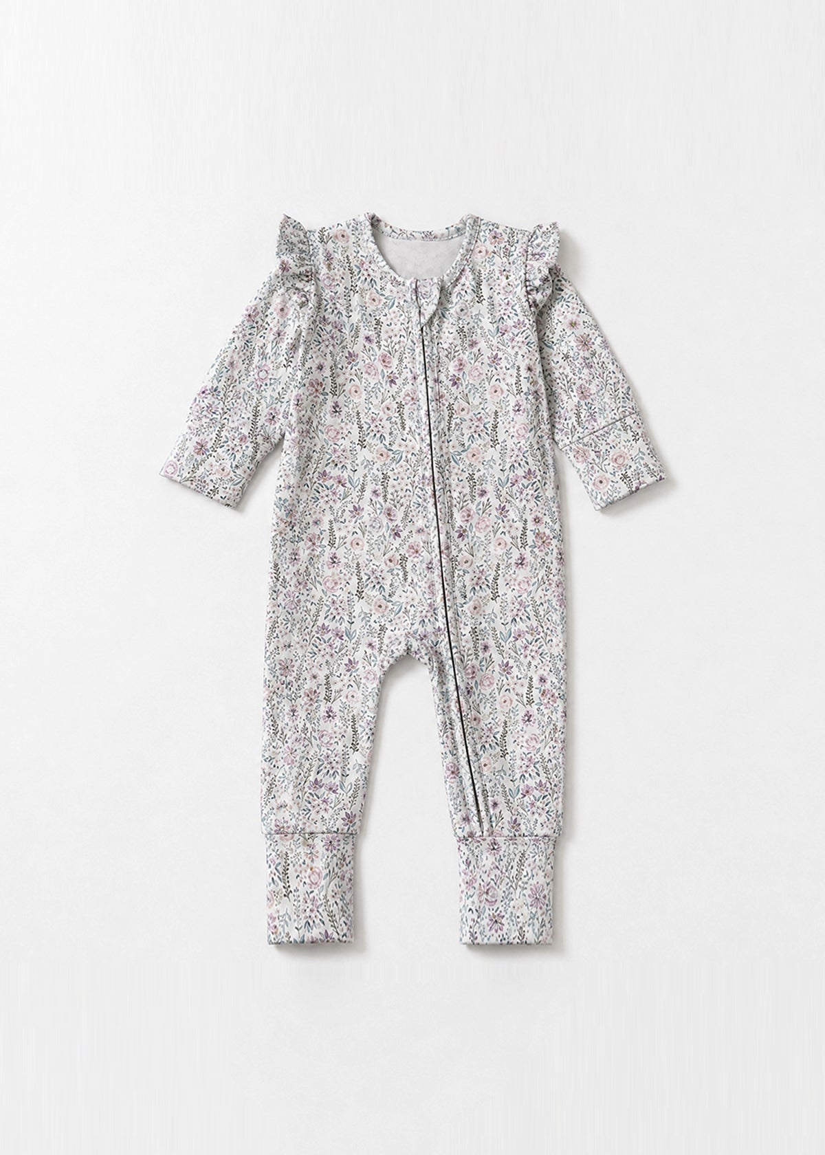 The Mabel + Honey Whimsical Wildflower Convertible Romper showcases long sleeves, straight legs, and charming ruffled shoulders, with a convenient zip-up front. Crafted from soft, stretchy knit fabric in a delicate pink and green ditsy floral print, this romper is displayed on a white background.