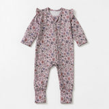The Mabel + Honey Soft Meadow Convertible Romper features long sleeves and ruffle shoulders, adorned with a pink and purple wildflower print from the Soft Meadow Collection, shown laid flat on a white background.