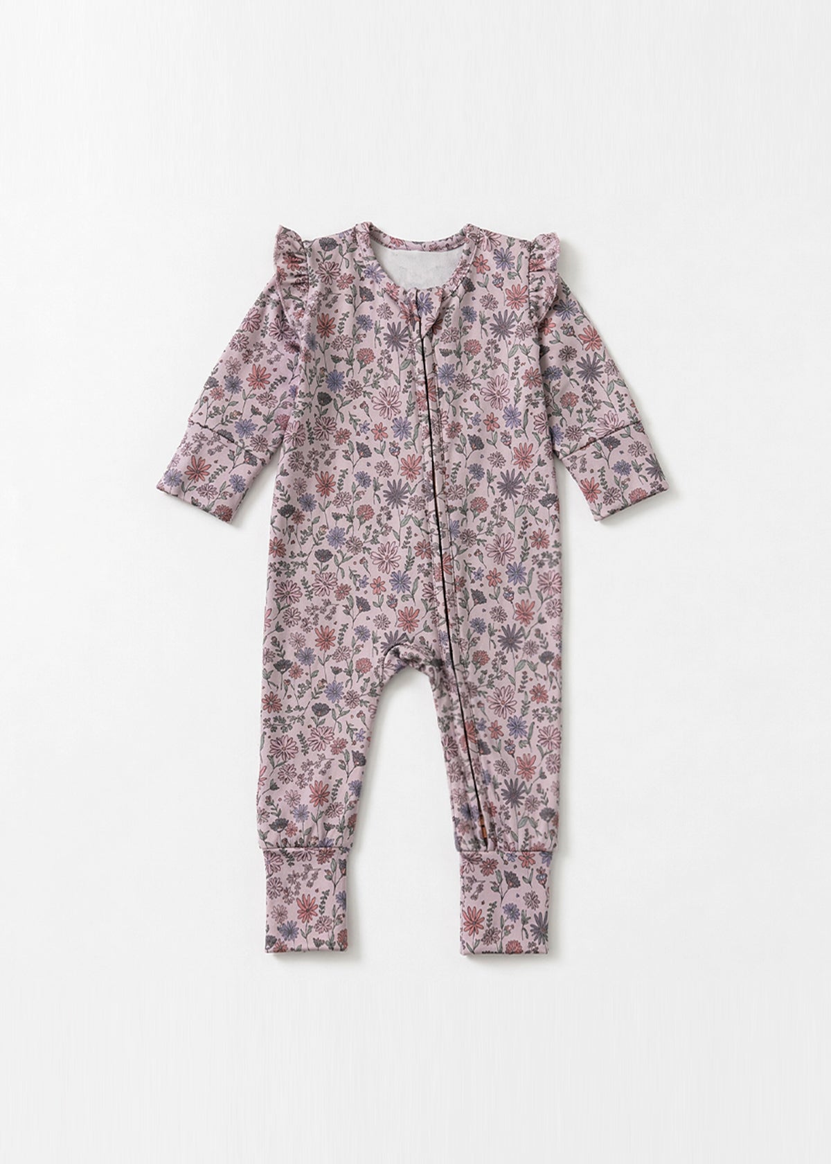 The Mabel + Honey Soft Meadow Convertible Romper features long sleeves and ruffle shoulders, adorned with a pink and purple wildflower print from the Soft Meadow Collection, shown laid flat on a white background.