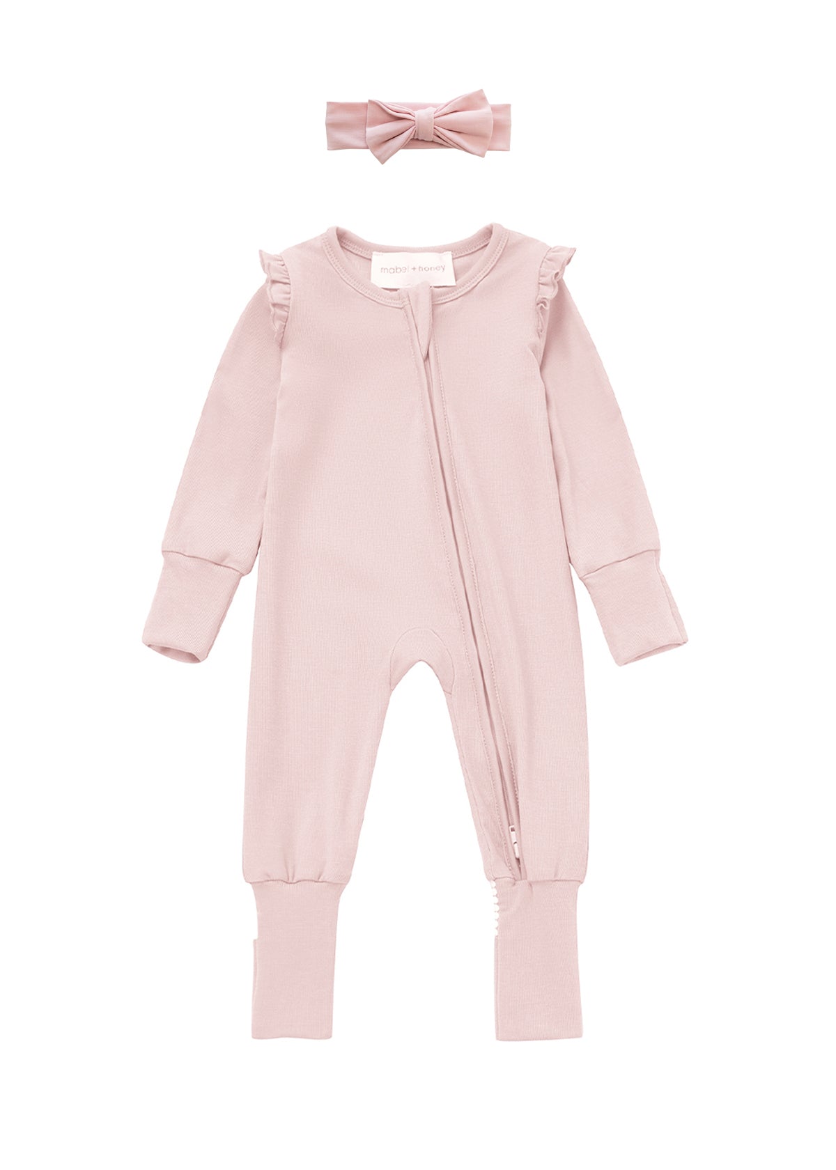 Introducing the Whimsical Wildflower Convertible Romper with Headband from Mabel + Honey—a soft light pink baby romper featuring long sleeves, ruffled shoulders, a diagonal zipper, and a convertible footed sleeper design for versatility and comfort. The set includes a matching pink fabric headband adorned with a bow displayed above the outfit.
