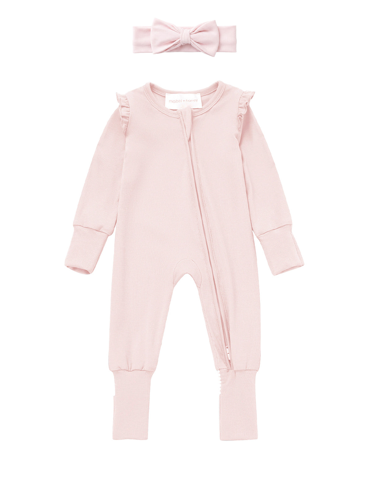 The Mabel + Honey Amelia Rose Convertible Romper features long sleeves, a zipper front, ruffled shoulders, and comes with a matching pink headband adorned with a bow, displayed flat on a white background.