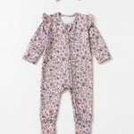 The Soft Meadow Long Sleeve Floral Print with Matching Headband by Mabel and Honey features a charming wildflower motif in soft pink, purple, and green tones. Crafted from cozy knit fabric, this adorable baby romper comes with ruffled shoulders and a coordinating headband, both beautifully displayed on a light background.