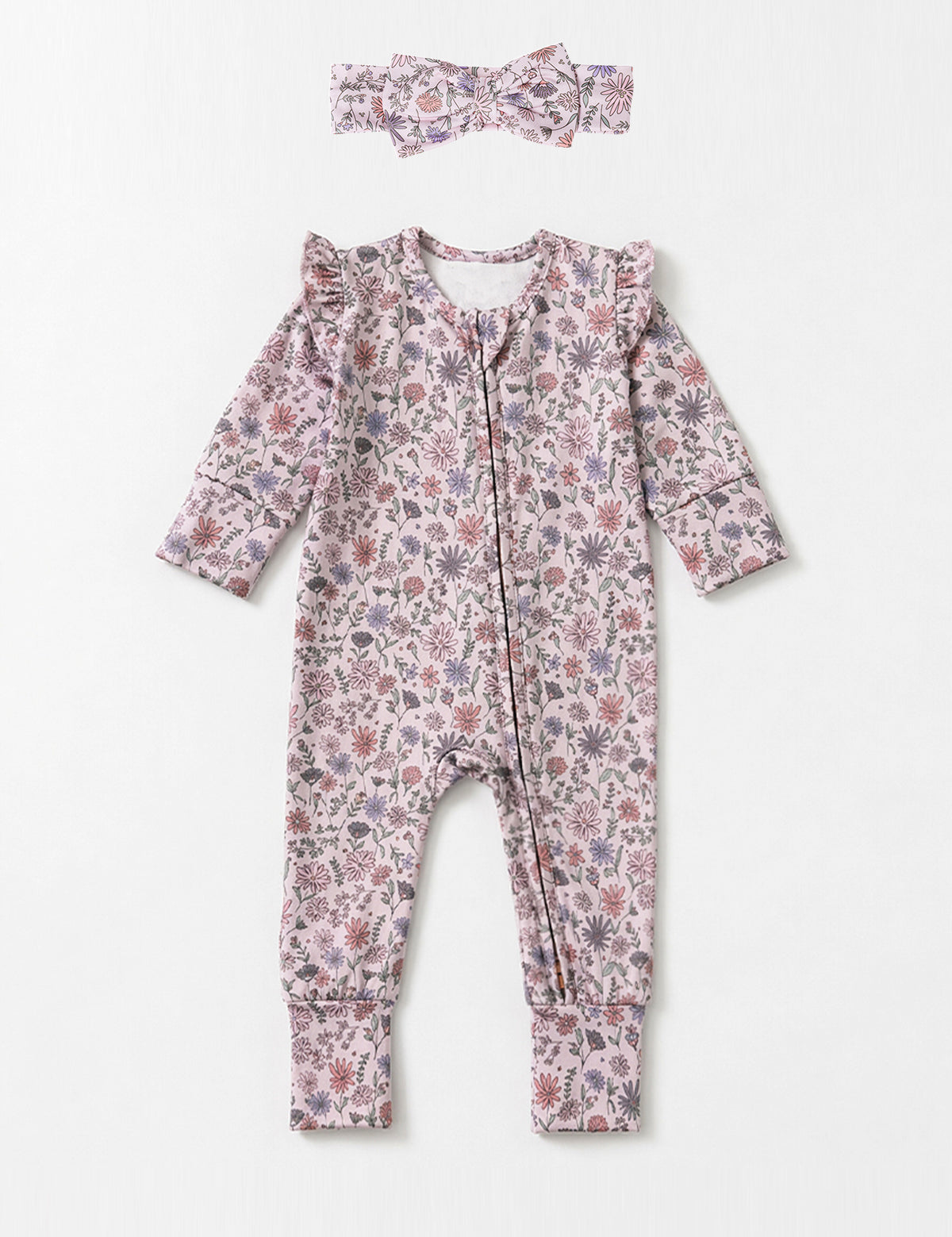 The Soft Meadow Long Sleeve Floral Print with Matching Headband by Mabel and Honey features a charming wildflower motif in soft pink, purple, and green tones. Crafted from cozy knit fabric, this adorable baby romper comes with ruffled shoulders and a coordinating headband, both beautifully displayed on a light background.
