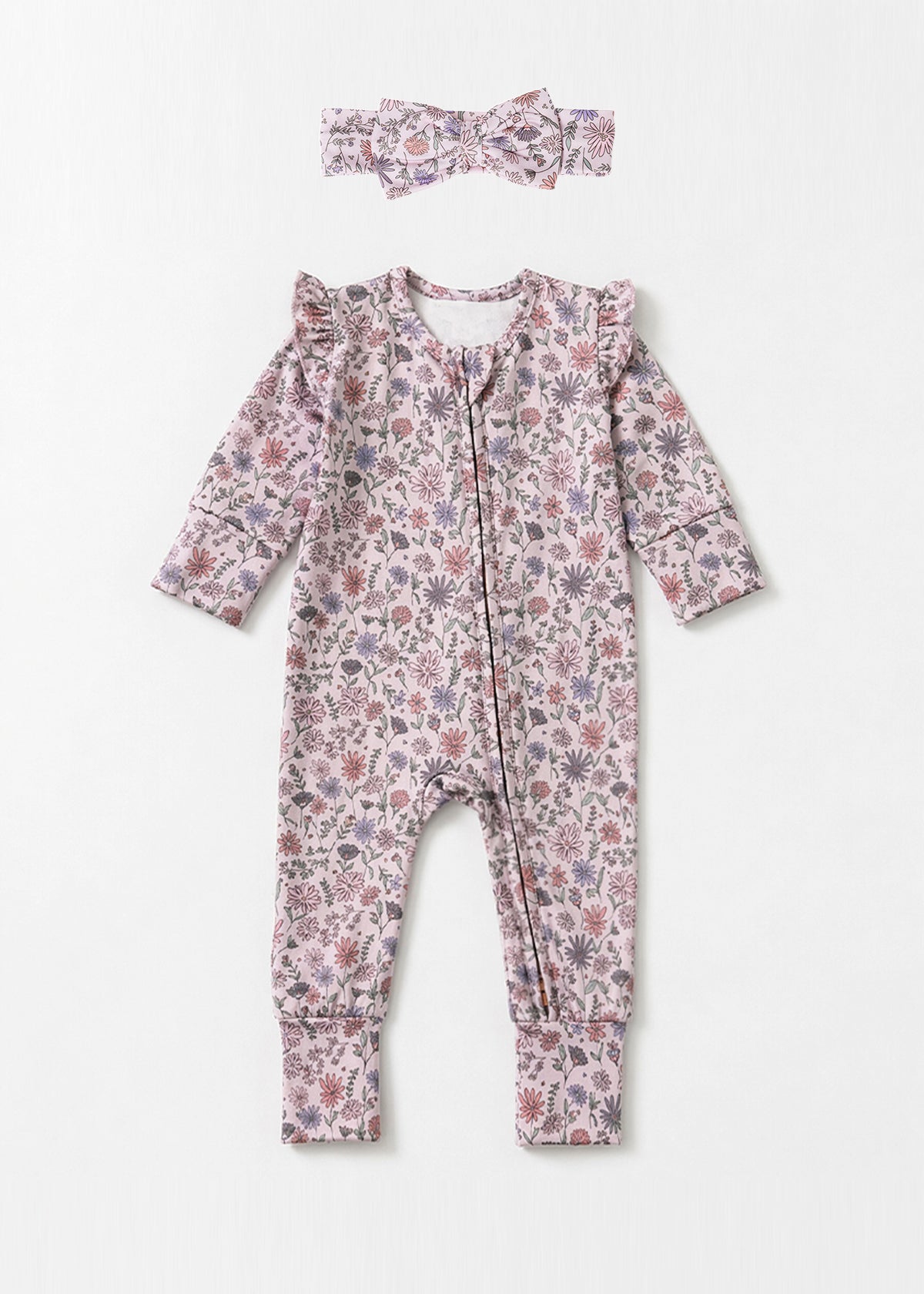 The Soft Meadow Long Sleeve Floral Print with Matching Headband by Mabel and Honey features a charming wildflower motif in soft pink, purple, and green tones. Crafted from cozy knit fabric, this adorable baby romper comes with ruffled shoulders and a coordinating headband, both beautifully displayed on a light background.