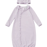 The Soft Meadow Newborn Gowns Long Sleeve Solid Gown with Matching Hat by Mabel + Honey features a lilac gown with ruffle trim along a diagonal front closure and an elasticized hem for easy changes. The set includes a matching hat accented with a front knot detail. Both pieces are crafted from soft fabric and are displayed on a white background.